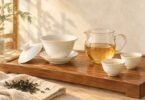 Illustration of a white porcelain gaiwan, glass pitcher and two small teacups on a wooden tray.