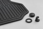 Illustration of a black rubber floor mat beside a loose cap, ring and hook-shaped retaining piece
