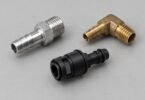 Three detached unbranded metal and plastic vacuum fittings on a gray surface