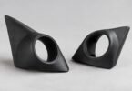 Two unbranded black tweeter mounting pods with empty round openings on a gray surface.