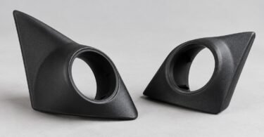Two unbranded black tweeter mounting pods with empty round openings on a gray surface.