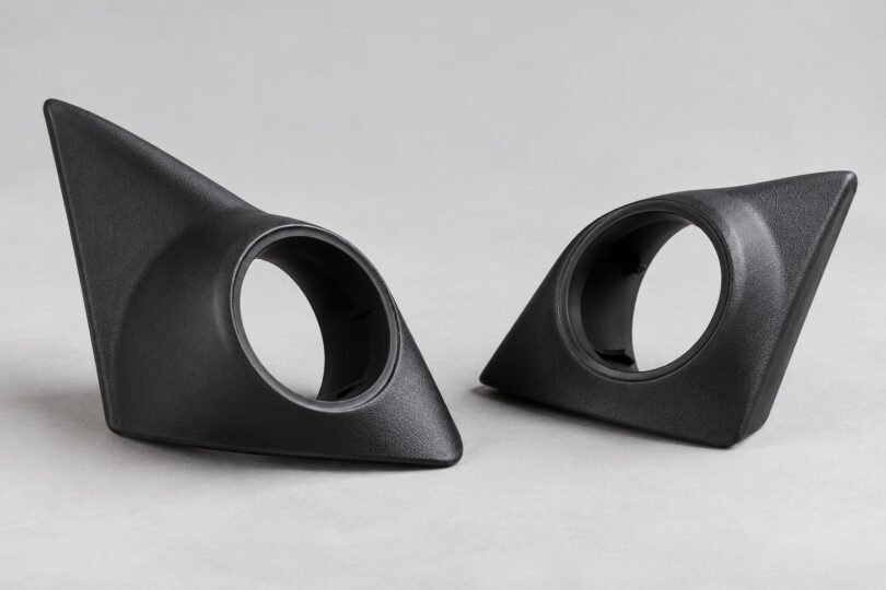 Two unbranded black tweeter mounting pods with empty round openings on a gray surface.