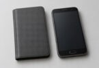 Closed unbranded charcoal folio cover beside a generic older smartphone with a blank screen and physical home button