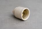 Generic unbranded ceramic lamp socket resting disconnected on a gray workbench