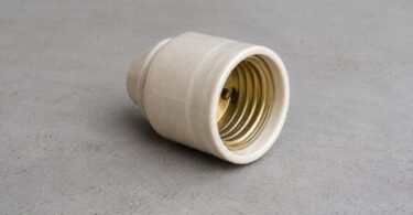 Generic unbranded ceramic lamp socket resting disconnected on a gray workbench