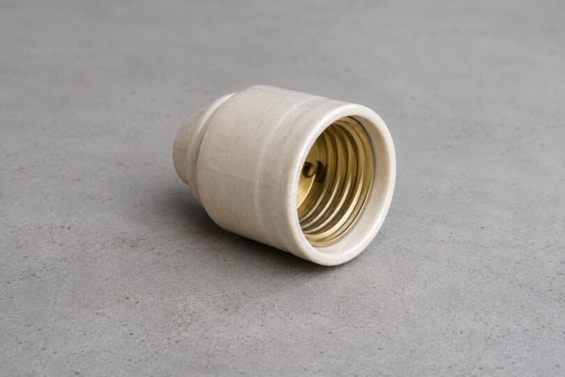 Generic unbranded ceramic lamp socket resting disconnected on a gray workbench