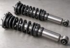Two unbranded coilover shock-and-spring assemblies on a gray workbench