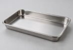 An empty rectangular stainless steel tray with rounded corners on a light gray surface