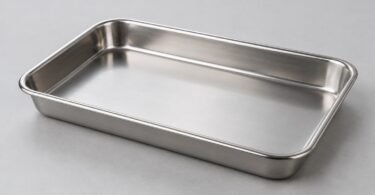 An empty rectangular stainless steel tray with rounded corners on a light gray surface