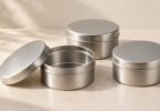 Illustration of three plain silver metal tins, including one open tin with its lid beside it.