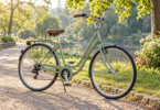 An unbranded pale green step-through bicycle parked on a sunlit path beside trees.