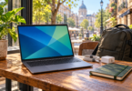 A generic laptop on a cafe table beside a charger, cable, notebook and travel backpack