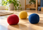 Three generic stitched juggling beanbags in red, yellow and blue on a sunlit wooden floor