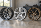 Original illustration of three unbranded alloy wheels in graphite, silver and bronze standing on a workshop floor