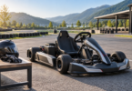 An unbranded electric-style go-kart parked beside an empty karting area, with a helmet and gloves on a bench.