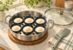 Illustration of six cooked eggs in six cups of an unbranded poaching pan, with a glass lid and silicone spatula beside it.