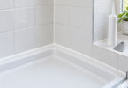 White tiled shower corner with a neat white joint beside a plain white cartridge and gray smoothing tool