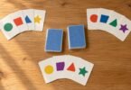 Unbranded cards with colorful geometric shapes arranged beside two card stacks on a wooden table