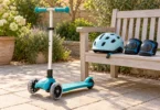Unbranded three-wheel children’s kick scooter beside a bicycle helmet and knee pads on a wooden garden bench