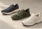 Charcoal, olive and off-white athletic shoes arranged on a light neutral surface