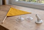 Yellow pennant, clear suction cups and an unbranded flag support on a wooden surface by a window
