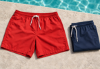 Generic red and folded navy swim trunks on a pale stone pool deck