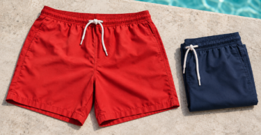 Generic red and folded navy swim trunks on a pale stone pool deck