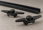 Two unbranded black bed rail cleats with thumbwheels beside a rail section