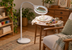 Conceptual unbranded magnifying floor lamp positioned over an embroidery hoop beside a chair.