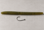 One unbranded dark fishing hook beside an olive-green soft-plastic worm on a neutral studio surface
