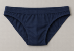 Unworn plain navy men’s bikini brief laid flat on a light gray surface