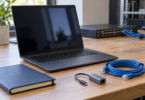 Generic laptop with a dark screen beside an Ethernet cable, USB-C Ethernet adapter and closed notebook