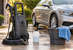 Generic pressure washer, foam cannon bottle and wash bucket beside a parked silver car