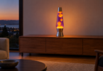 A tall unbranded lava-style lamp with amber wax and violet liquid on a clear wooden sideboard at dusk.