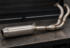 An unbranded two-into-one motorcycle exhaust assembly with a steel muffler on a workshop bench.