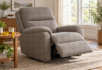 A gray fabric recliner with its footrest extended beside a table with a tape measure.