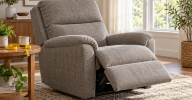 A gray fabric recliner with its footrest extended beside a table with a tape measure.