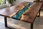 A finished walnut river table has a blue-green resin channel between natural wood edges and black metal legs in a sunlit room.