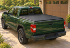 Illustration of a green pickup with a closed black bed cover beside a garage